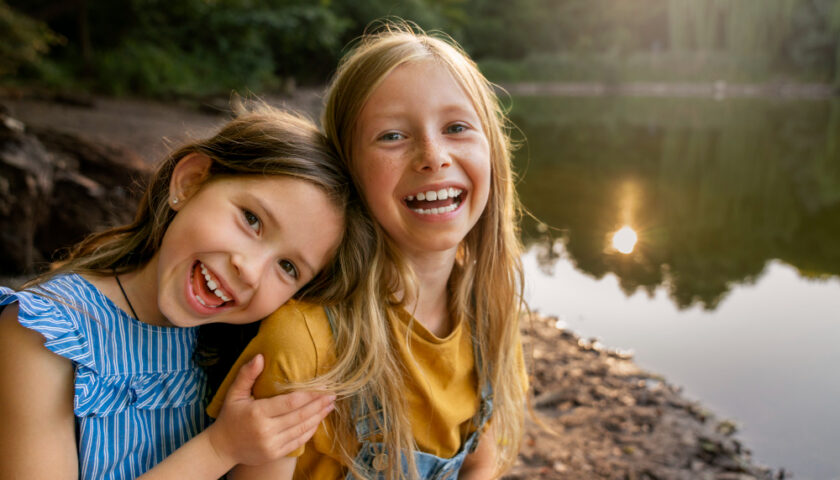 deux jeunes enfants souriants auprès d'un lac