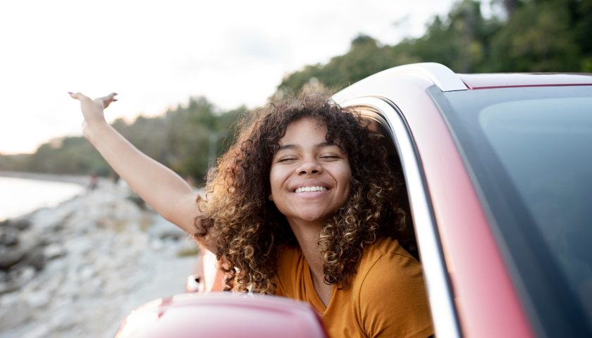 Une fille souriante en voiture, proche de la mer